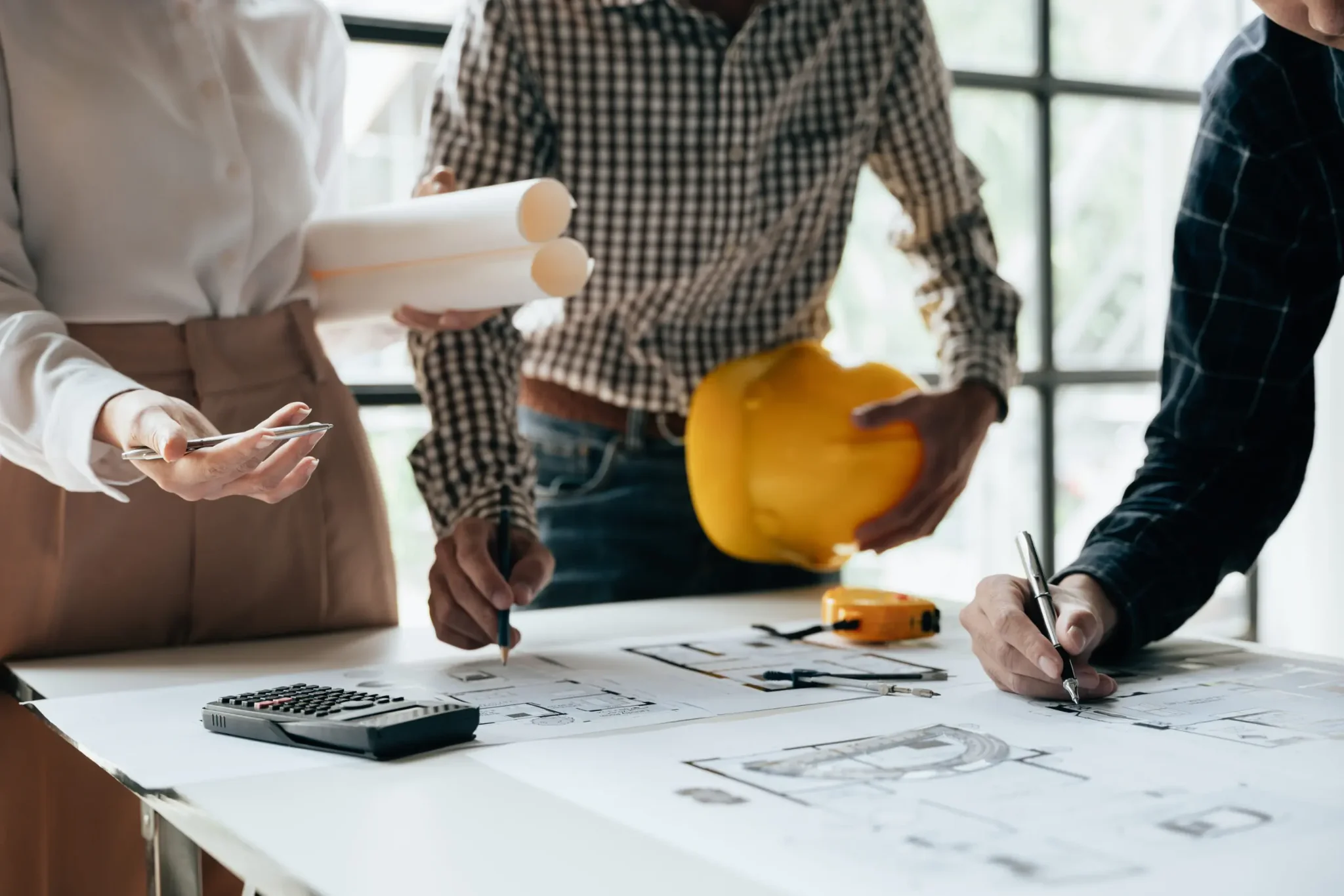 Architects reviewing a set of blueprints spread out on a table.