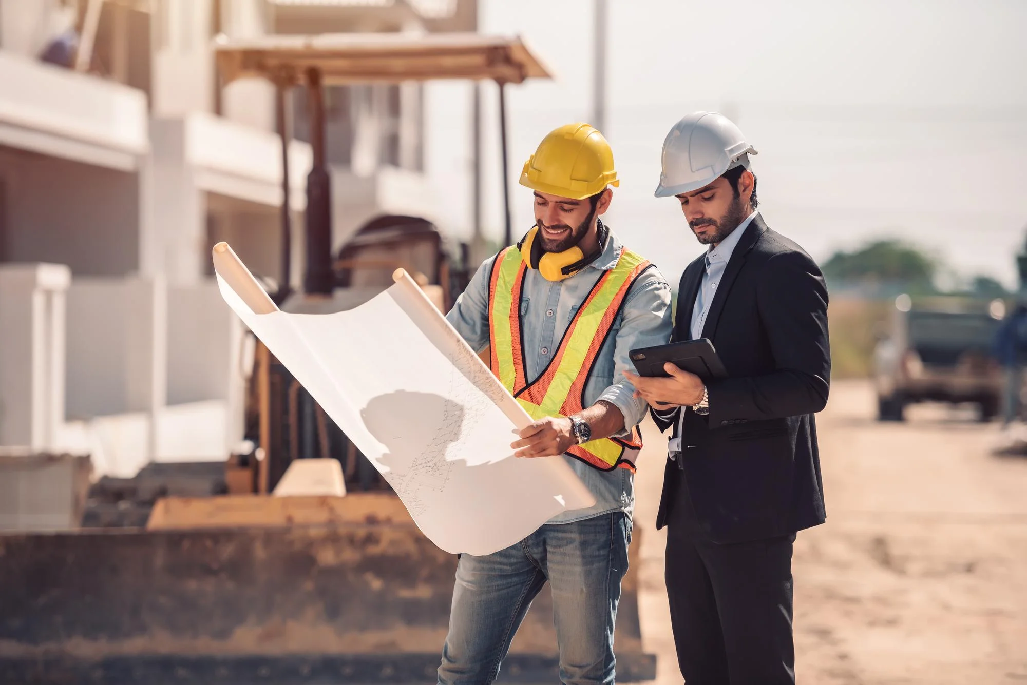 Architect and construction worker manager holding digital tablet and blueprints onsite.